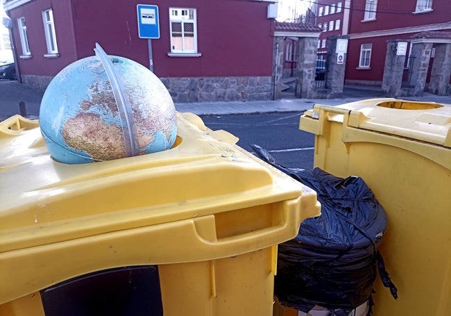 Bola del mundo en la basura, en un contenedor de plástico.