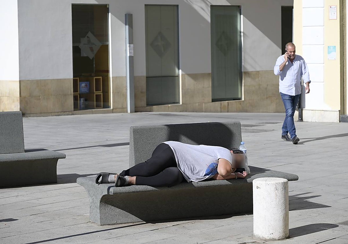 Una mujer duerme en un banco de la plaza de España a plena luz del día junto al Ayuntamiento.