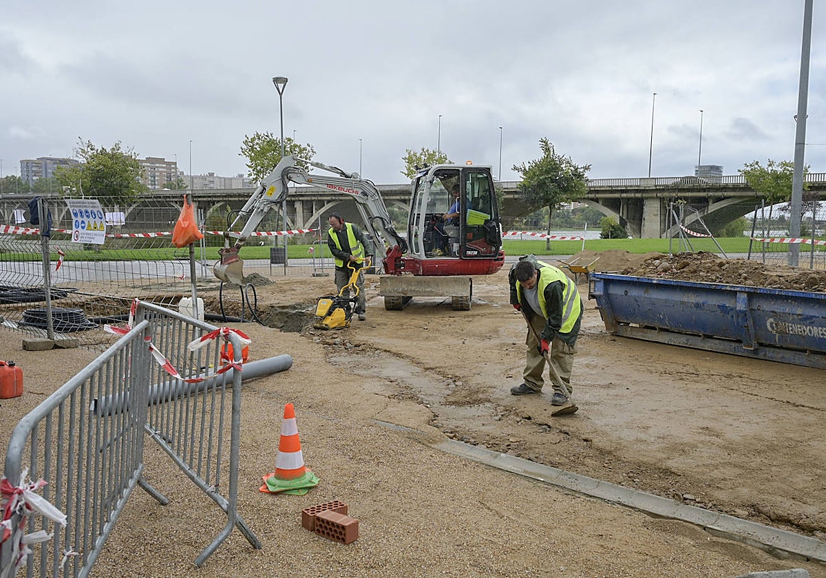 Los operarios preparan las instalaciones para colocar los baños en el parque del río.