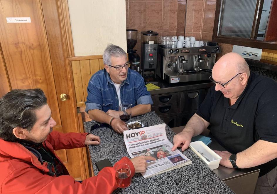 José Antonio Real comenta la actualidad con dos de los clientes, Emilio y Jose, con el ejemplar de HOY sobre la barra.