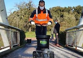 Un operario de Conyser esparciendo la sal por una pasarela peatonal.
