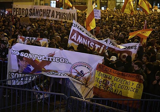 Decenas de personas con banderas y pancartas durante una concentración en contra de la amnistía frente a la sede del PSOE en la calle Ferraz.