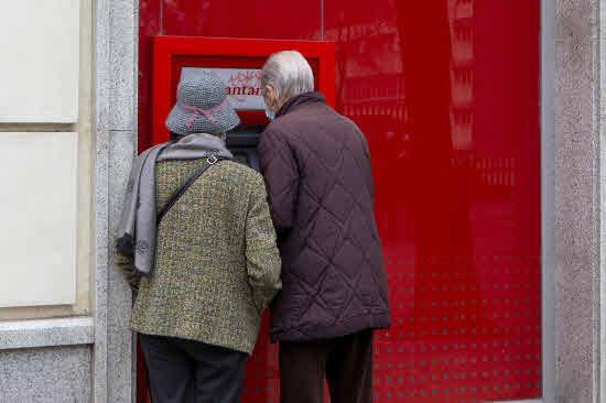 Foto de archivo de dos mayores retirando dinero de un cajero 