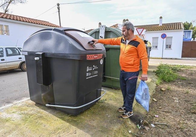 Un pacense se dirige al contenedor marrón, que solo lleva una franja de ese color, en Alcazaba el 2 de enero, aunque está precintado y no se puede abrir aún.