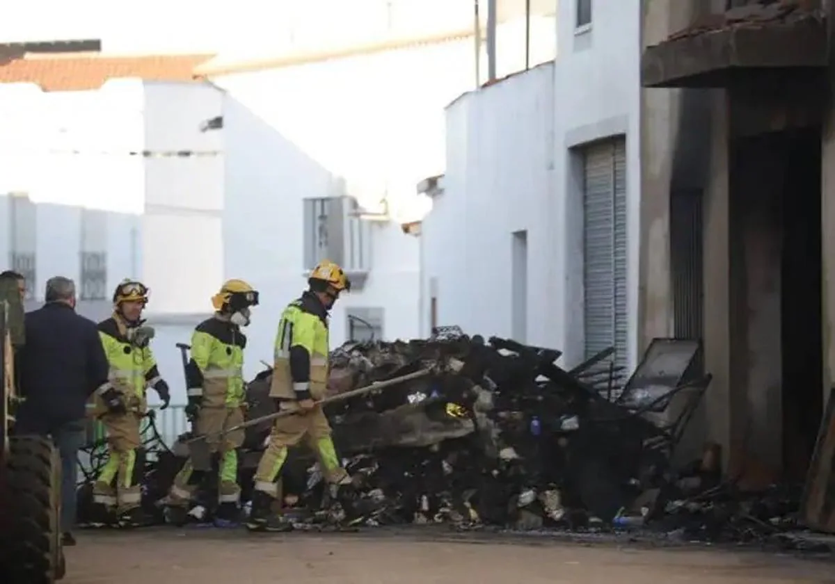 Bomberos de la Diputación sacando los enseres que había en la vivienda incendiada.