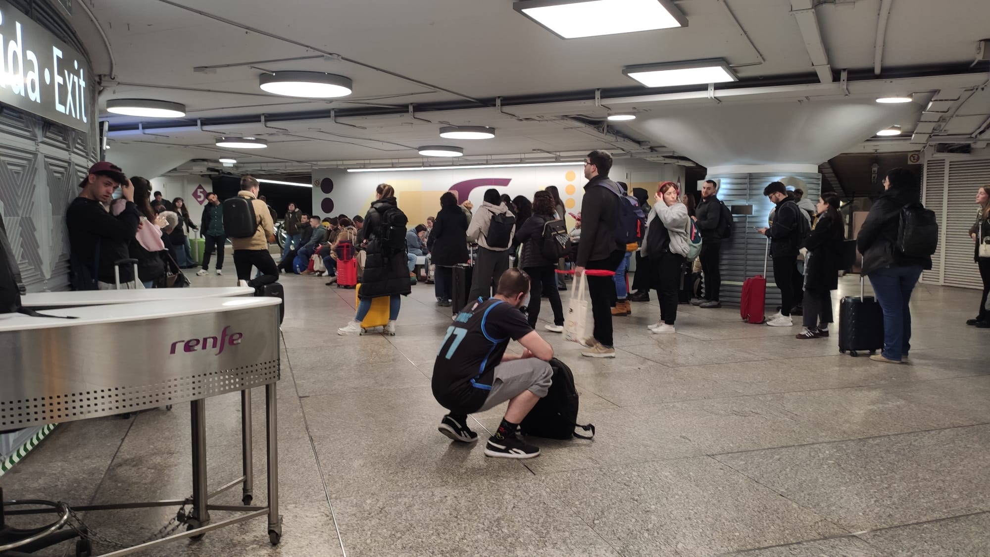 Pasajeros esperando en la estación de Atocha, en Madrid, tras anunciarse la demora de un tren con destino a Puertollano.