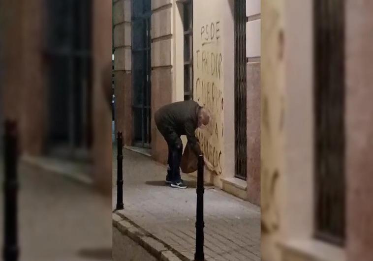 Un hombre de avanzada edad pinta la fachada de las oficinas del PSOE local y provincial en Badajoz