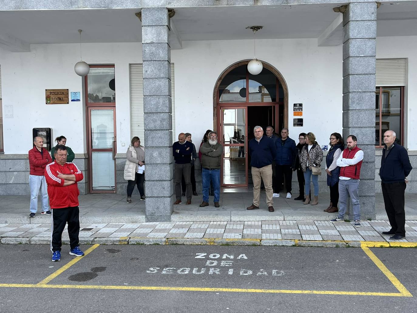 Asistentes al minuto de silencio guardado en la puerta del Ayuntamiento de Alconchel este lunes.