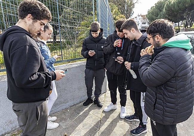 Alumnos del Virgen del Puerto, con el móvil durante el recreo fuera del recinto educativo.