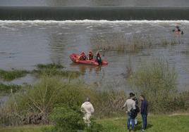 Un equipo de los bomberos de Badajoz se ha metido en el río a mediodía para buscar al menor. En la orilla, algunos familiares.