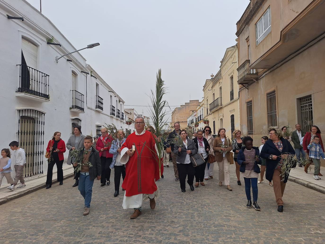 Imagen principal - Arriba, momento de la procesión del Domingo de Ramos. Abajo, grupo de portadores y nazarenos de la Hermandad del Cristo de Alconchel, tras la procesión del Lunes Santo.