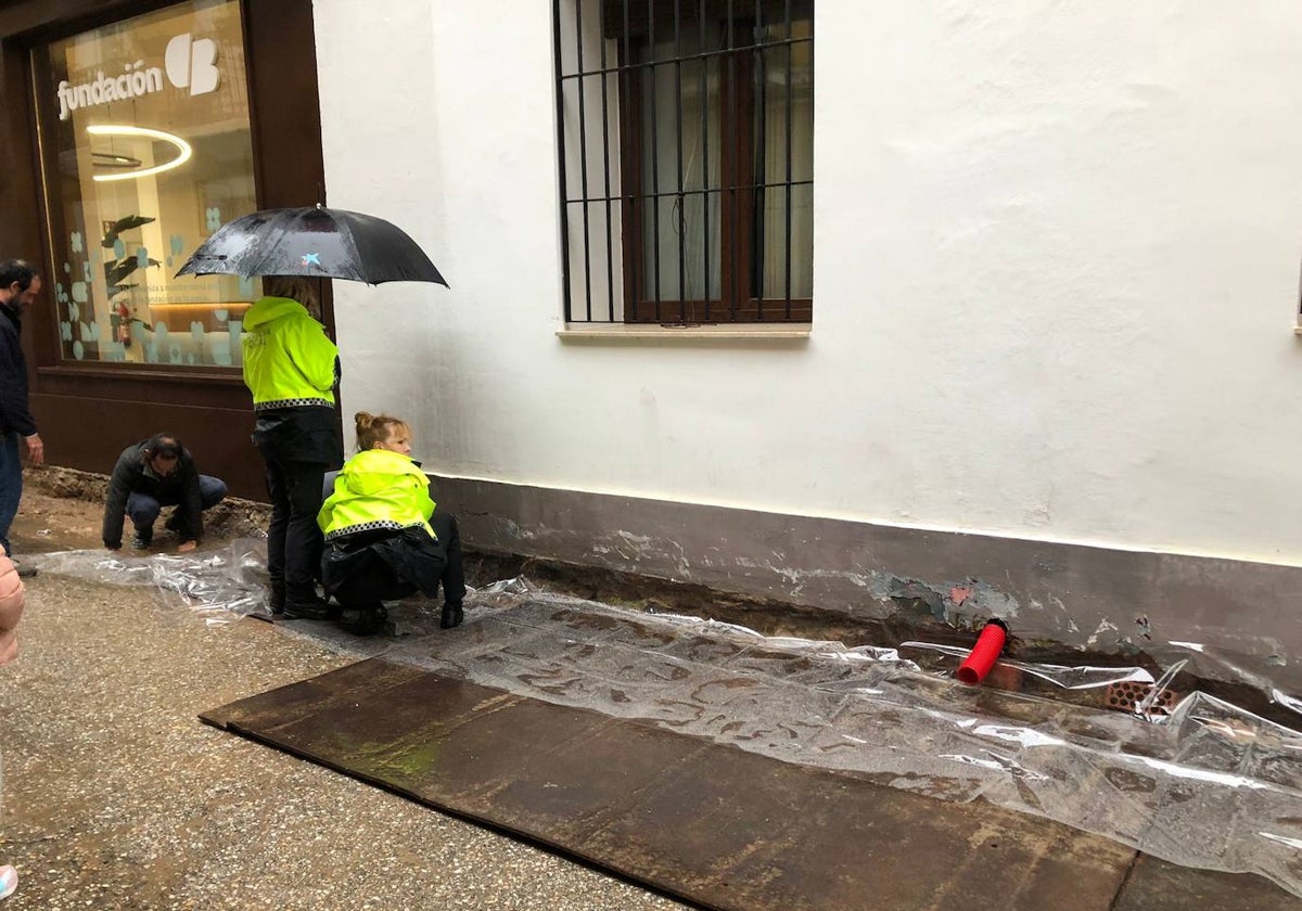 La Policía Local trata de detener la filtración de agua hacia las viviendas colocando plásticos en la calle Montesinos.