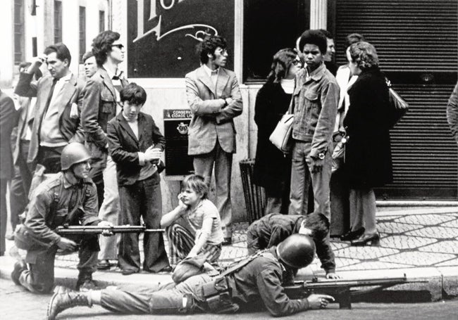 Militares portugueses vigilan una calle rodeados de niños y adultos el 25 de abril de hace medio siglo.