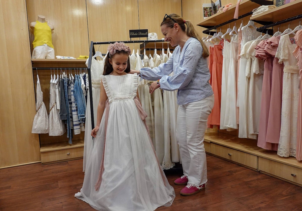 Elena Guadalupe se prueba un traje de comunión con la ayuda de su madre en la tienda Rafaello de Badajoz.