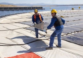 Dos operarios reponen un módulo solar en la planta fotovoltaica flotante ubicada sobre la presa de Sierra Brava.