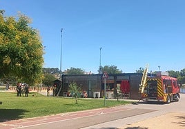 Efectivos de bomberos y Policía Nacional observan el lugar del origen de las llamas en el bar 'El muelle del Guadiana'.
