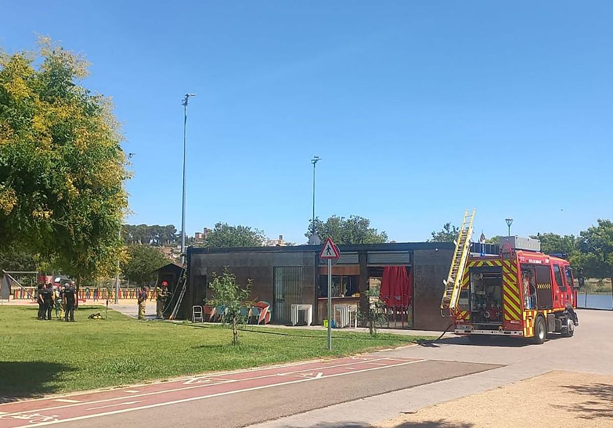 Efectivos de bomberos y Policía Nacional observan el lugar del origen de las llamas en el bar 'El muelle del Guadiana'.