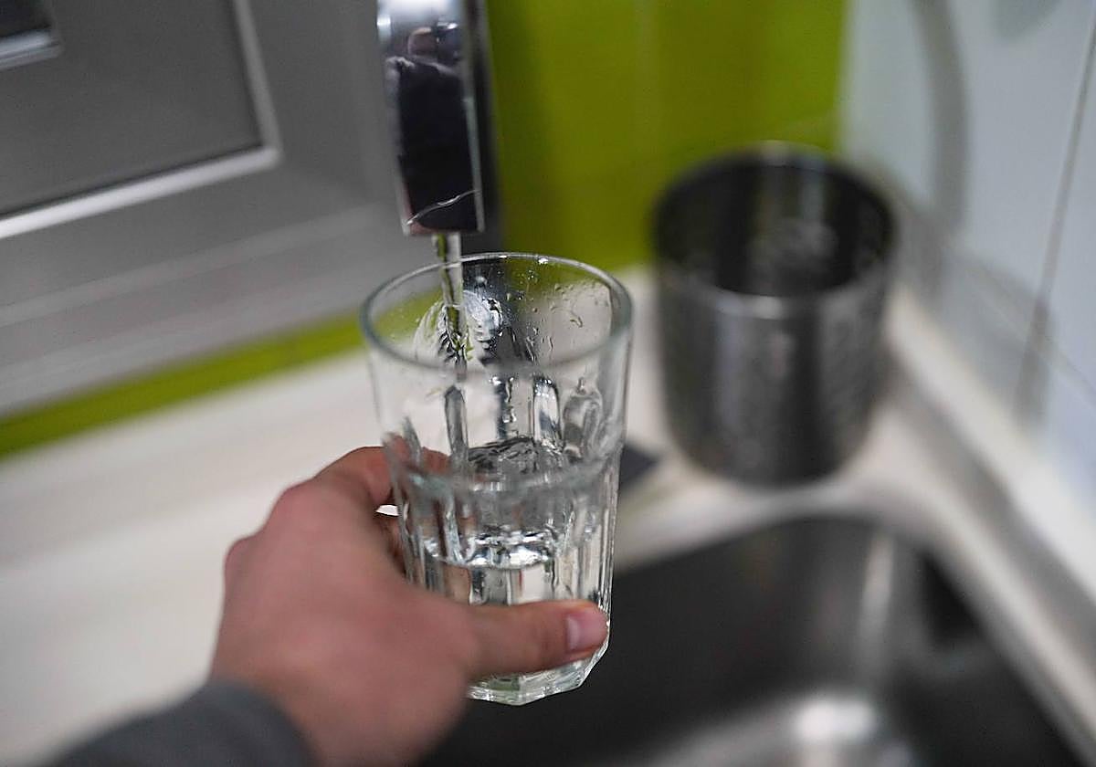Una persona se llena un vaso de agua para beber