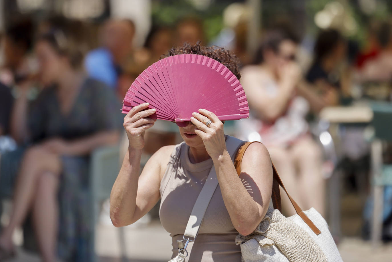 Una mujer se protege con un abanico del sol y del calor