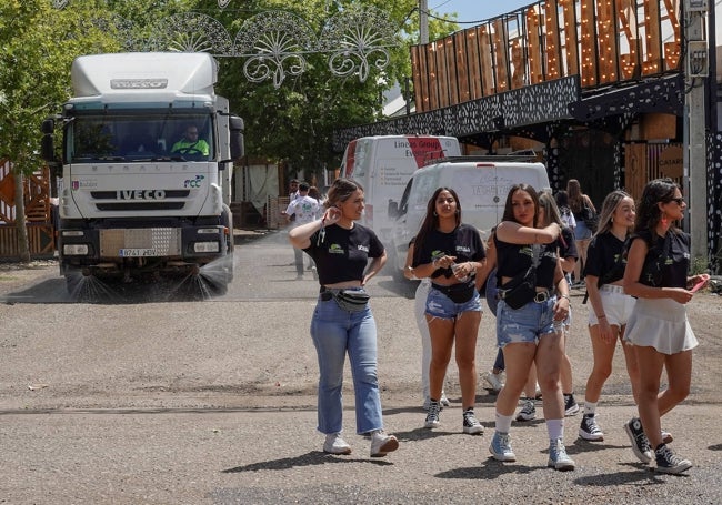 Relaciones públicas de las casetas de baile este sábado. Al fondo, un camión regando el suelo del ferial.