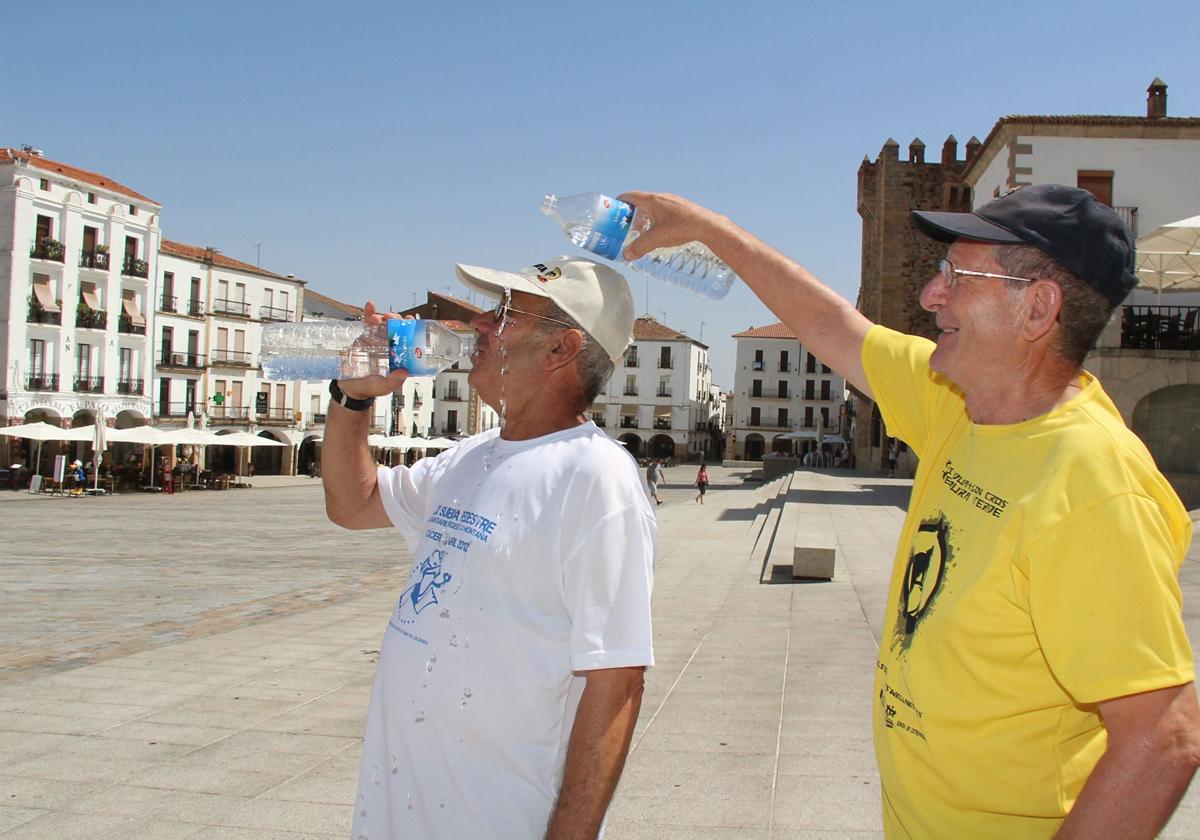 Dos hombres se refrescan en la plaza Mayor de Cáceres.