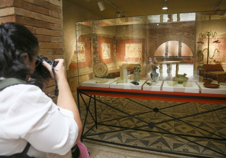 Estancia de una casa en el Museo con piezas de cerámica, suelo de mosaico y pinturas en la pared.