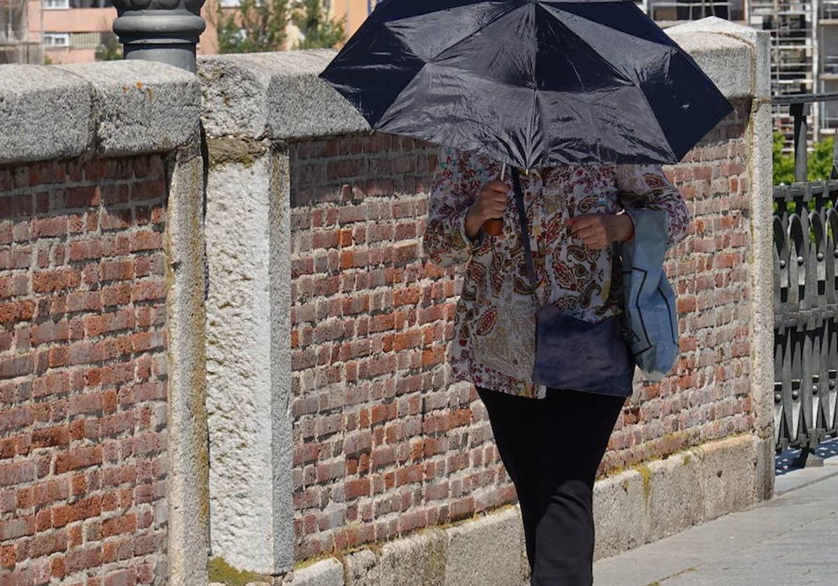 Imagen de archivo de una mujer caminando por el Puente de Palmas bajo un paraguas para protegerse del calor.