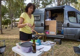 Una huésped del camping de Mérida prepara la cena, con su furgoneta al fondo.