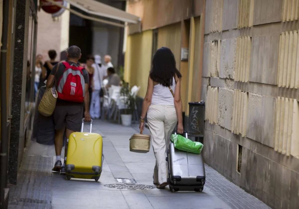 Turistas llevando maletas por la calle.