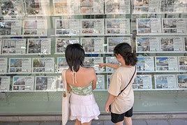 Dos chicas miran anuncios de pisos para alquilar en una inmobiliaria