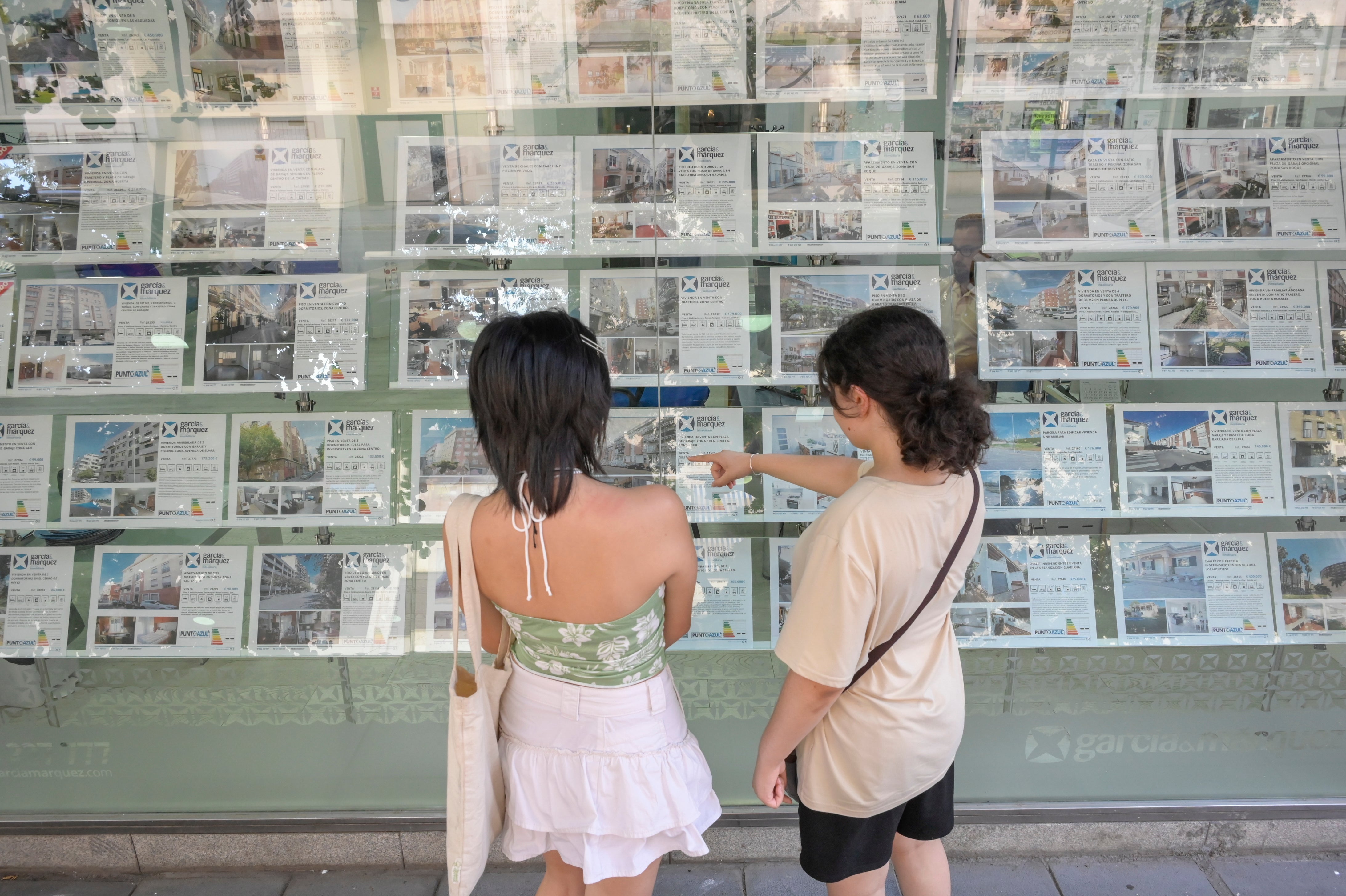 Dos chicas miran anuncios de pisos para alquilar en una inmobiliaria