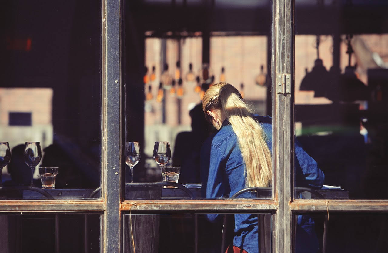 Fotografía de una mujer de espaldas en un local de hostelería.