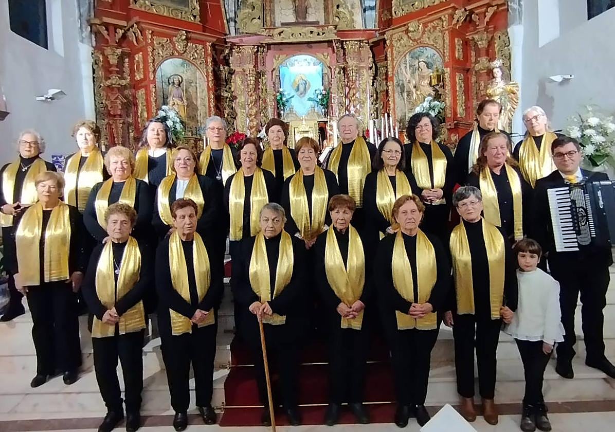 Imagen principal - Arriba, componentes del Coro de Nuestra Señora de los Santos de Táliga, que amenizarán con la misa extremeña la eucaristía de este 15 de agosto. Abajo, lona de las fiestas patronales y merchandising que pone en venta la Hermandad de la Virgen de la Luz.