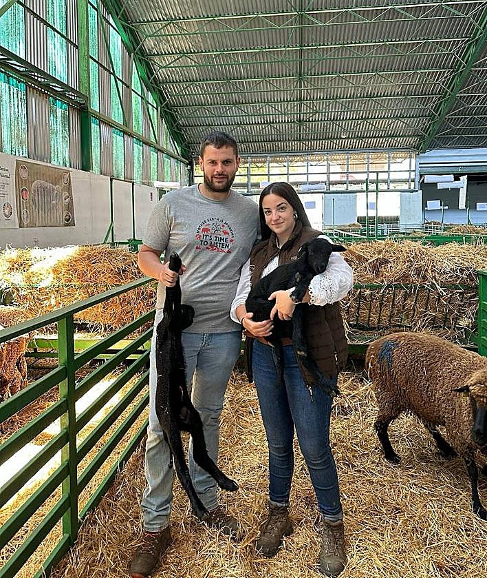 Imagen secundaria 2 - Arriba, panorámica de Ángela Santiago junto a su ganado en los montes de León. Abajo, la ganadera dando de mamar a corderos merinos y junto a su pareja, Daniel Cañón, en uno de los certámenes ganaderos de Zafra.