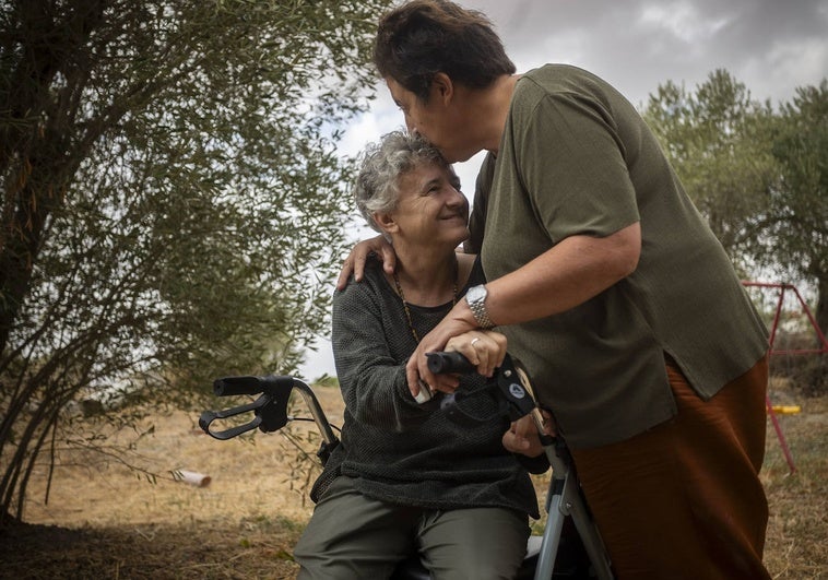 Elena sentada en su andador, junto a su esposa Tati, en la finca que han alquilado en la localidad cacereña de Brozas.