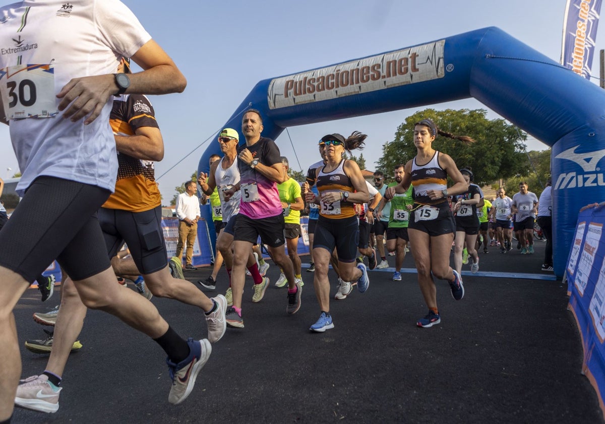 Imagen principal - Tres momentos de la carrera solidaria, con la salida en la imagen superior, el ganador, Julián polo, en el momento de entrar en la meta, y un grupo de participantes, sobre estas líneas.