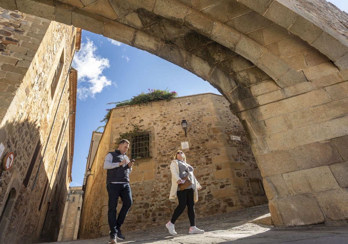 Una pareja pasa bajo el Arco de la Estrella, acceso por excelencia a la Ciudad Monumental de Cáceres.