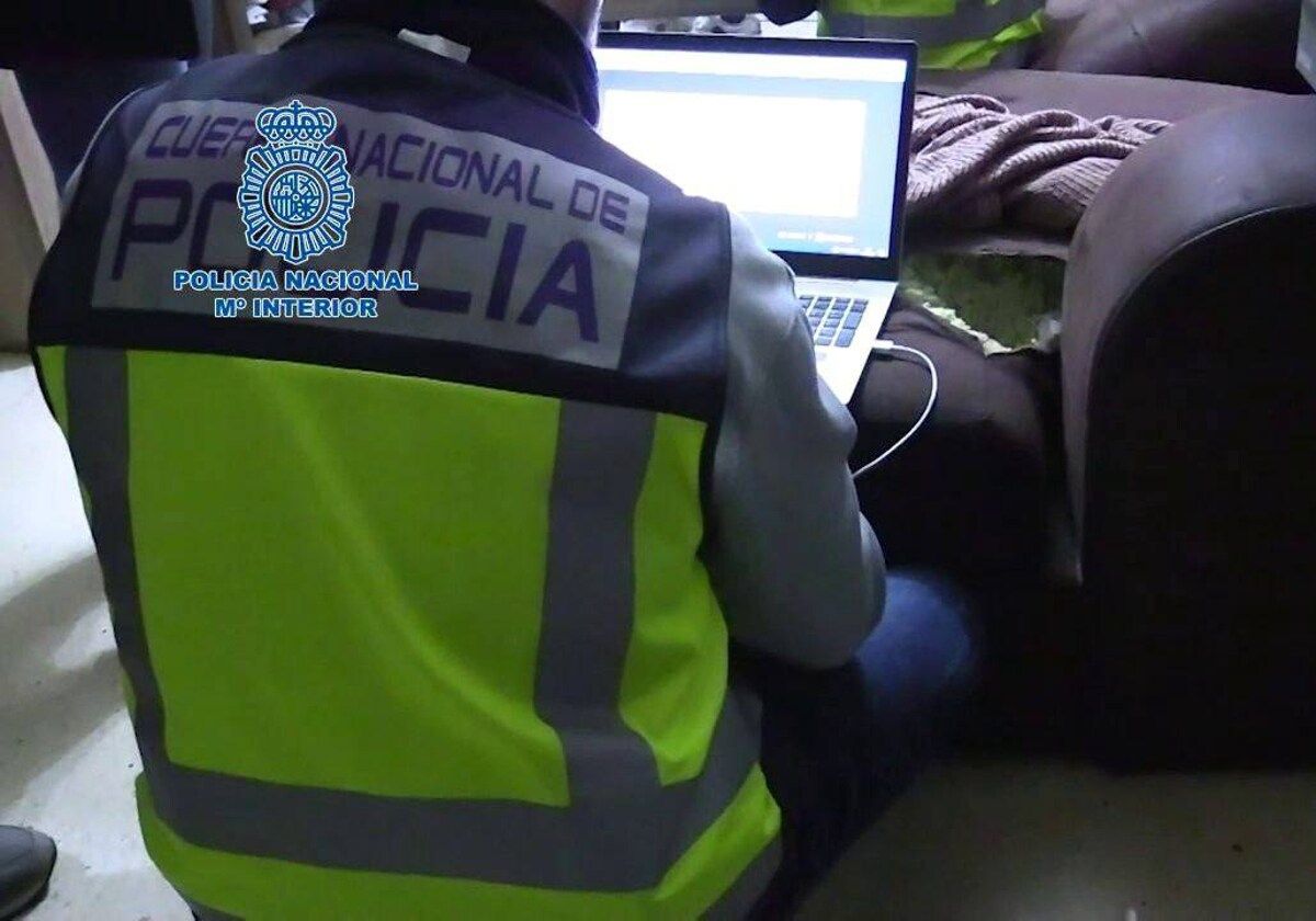 Un agente de la Policía Nacional examina un ordenador incautado en una operación contra ciberdelincuentes