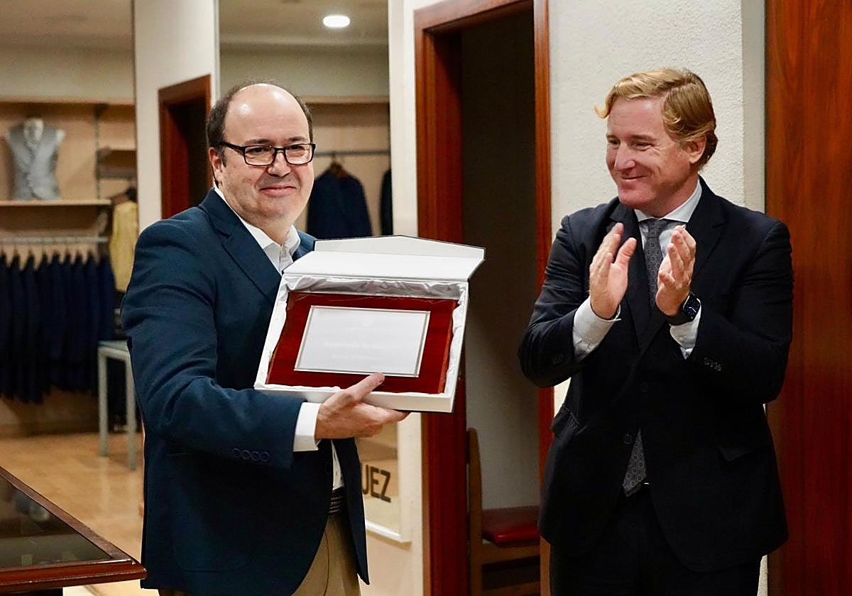 Felipe Velázquez, responsable de la sastrería familiar, recoge la placa conmemorativa de las manos del alcalde de Badajoz.