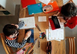 Dos niños haciendo las tareas en casa con una 'tablet' cada uno.