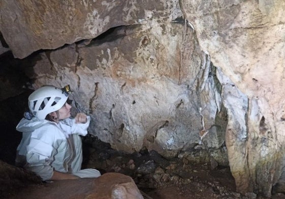 Imagen de una visitante contemplando una de las manos que alberga la cueva de Maltravieso.