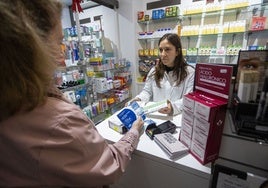 Una mujer compra mascarillas y un test de gripe y covid en una farmacia de Cáceres.