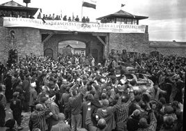 Prisioneros de Mauthausen saludan a la 11ª División Acorazada de los Estados Unidos por su liberación bajo una pancarta escrita en español sobre sábanas castrenses.