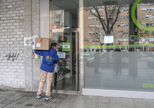 Un repartidor ante la puerta cerrada de la clínica veterinaria Animax, en Badajoz.