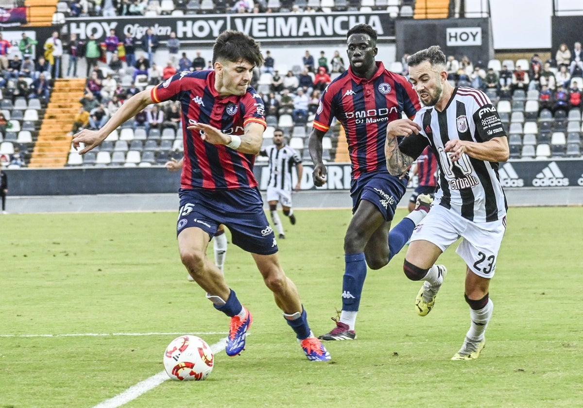 Santi Luque y Pablo Cidoncha disputan un balón en presencia de Moussa, en el Badajoz-Extremadura.