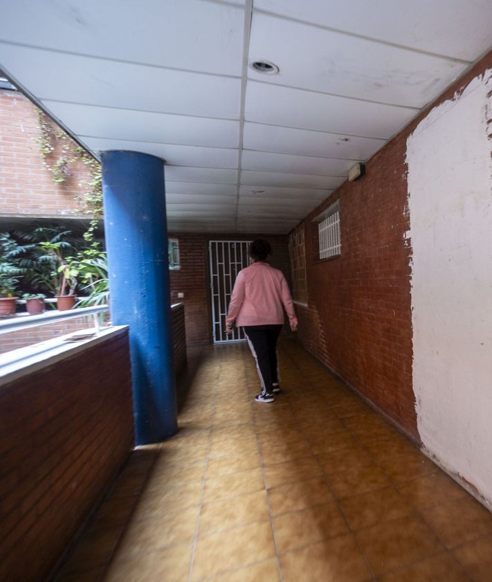 Imagen secundaria 2 - Agustina López señala las manchas de humedad en el techo. En otra imagen, las escaleras del bloque siguen sin mantenimiento. Debajo, vivienda tapiada tras haber sido okupada.