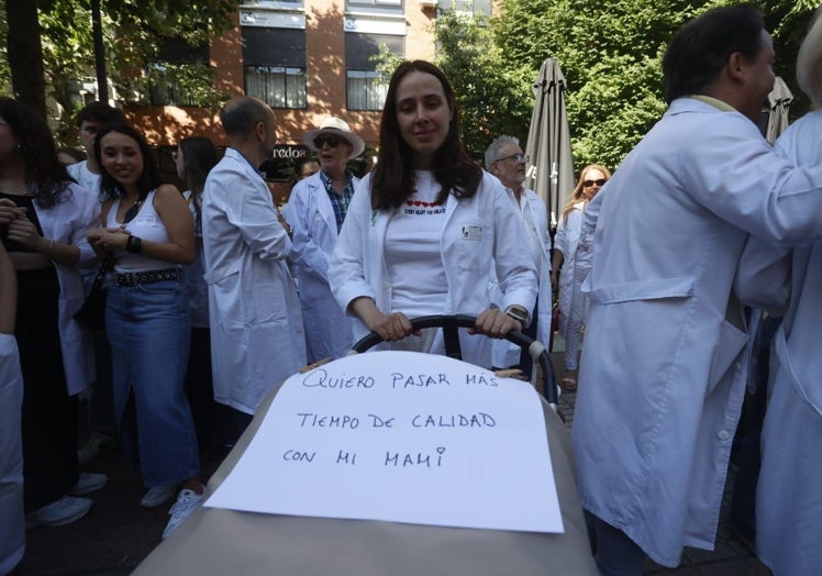 La cardióloga María José Romero junto a su hijo de cuatro meses y medio en el carrito y una pancarta para reivindicar mejoras laborales.