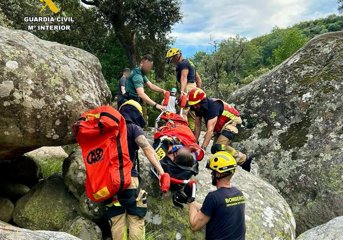Imagen principal - El equipo de rescate tuvo que sortear grandes piedras para llevar a la mujer hasta la ambulancia que la esperaba en una pista.