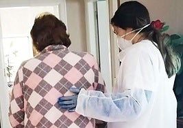 Imagen de archivo de una auxiliar de ayuda a domicilio ayudando a una persona mayor en su domicilio.