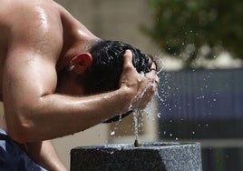 Un hombre se refresca en ua fuente del calor sofocante.
